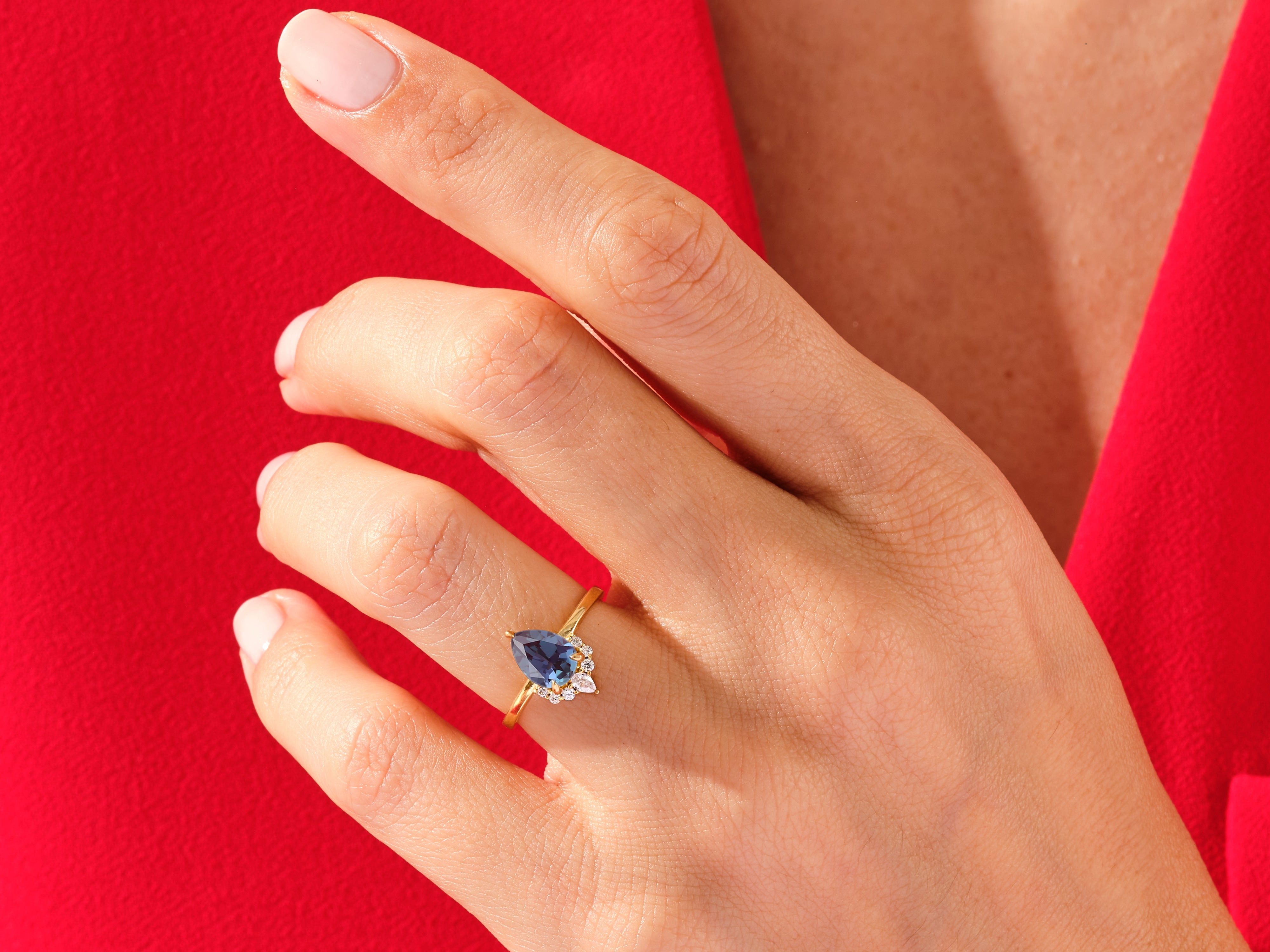 Pear-shaped sapphire and diamond ring on a hand