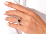 Hexagonal blue gemstone ring with diamonds on a hand