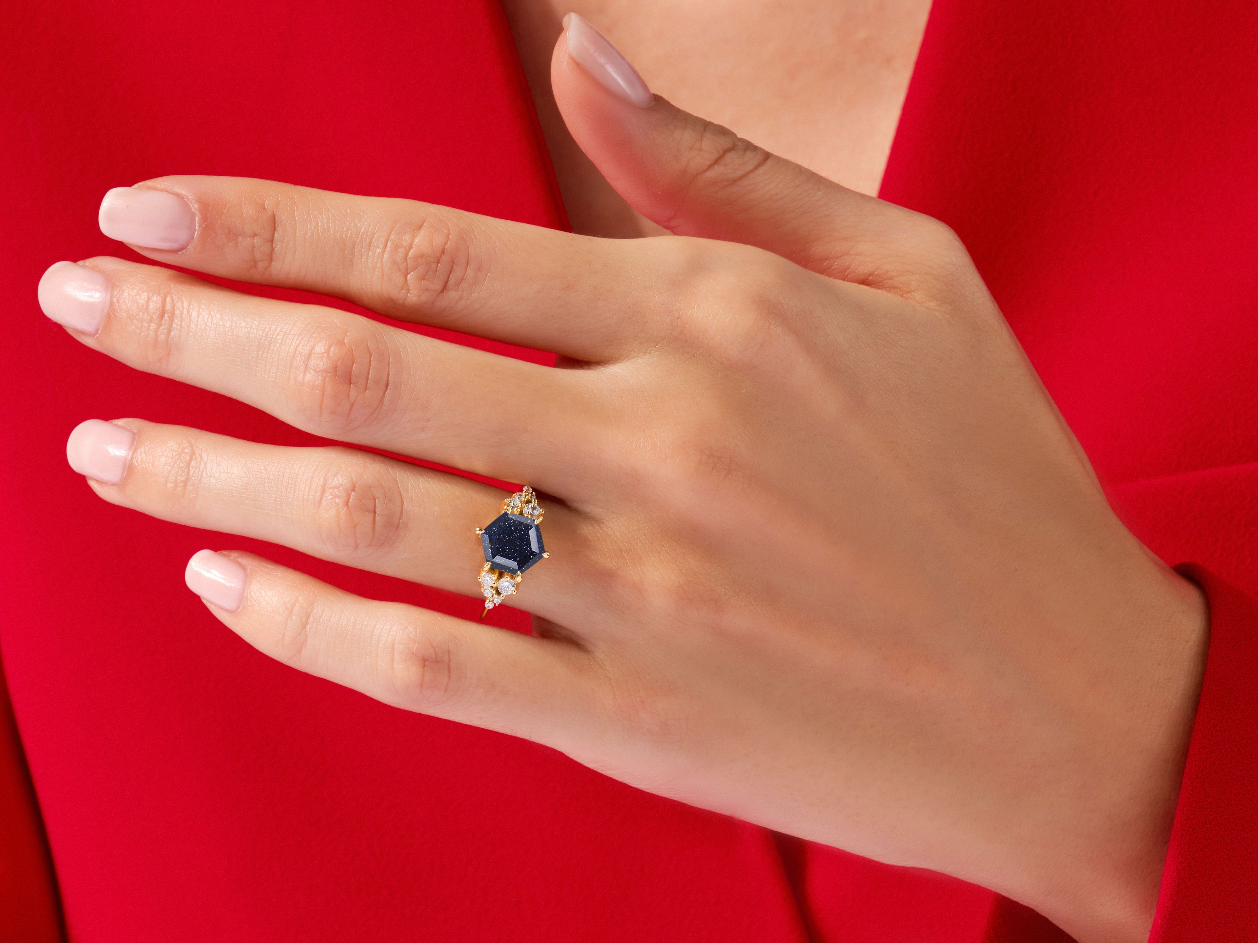 Gold ring with blue stone and diamonds on a red background