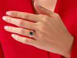 Gold ring with blue stone and diamonds on a red background