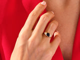 Gold ring with dark blue gemstone and diamonds on hand