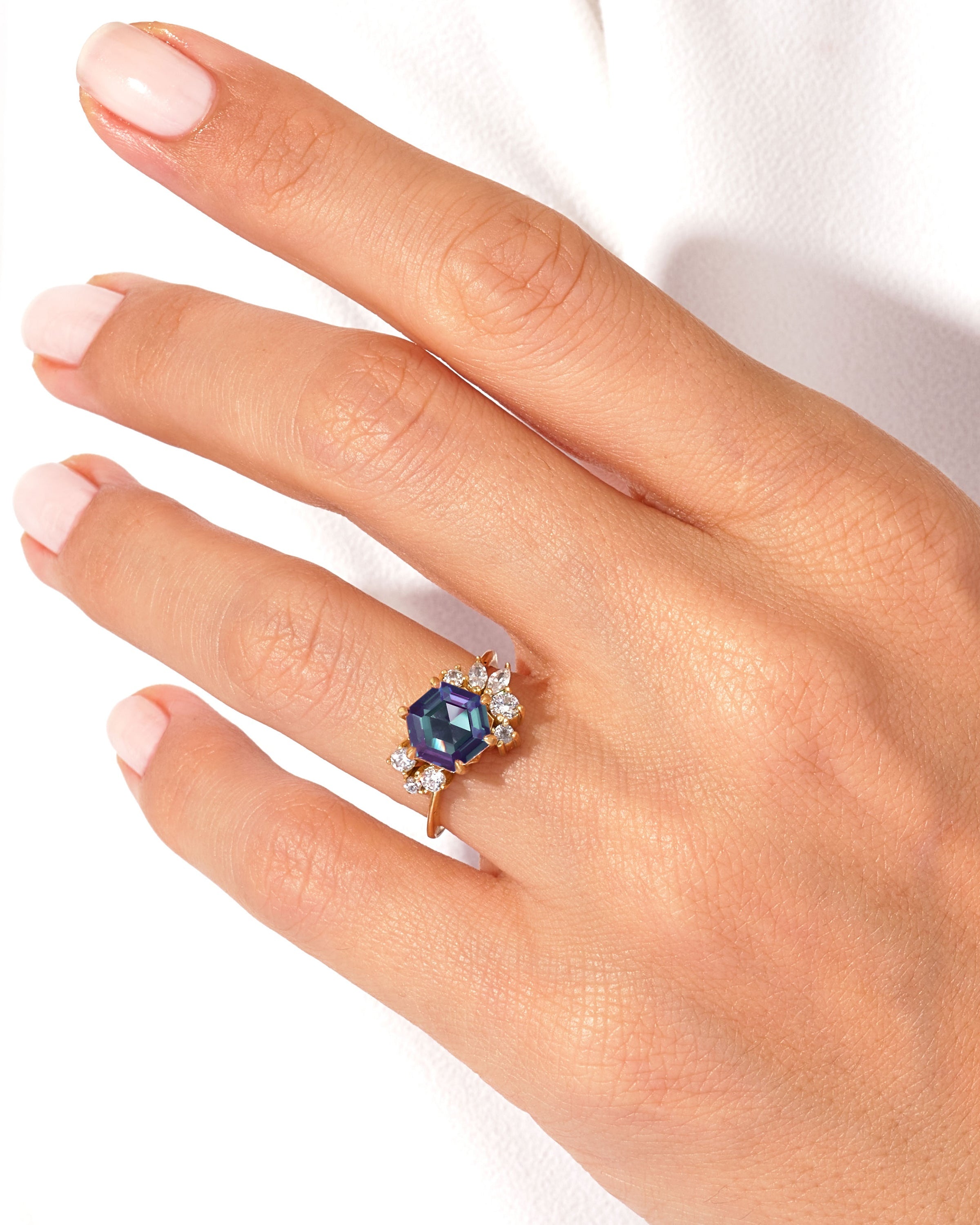 Hexagonal gemstone ring with diamonds on a woman's hand
