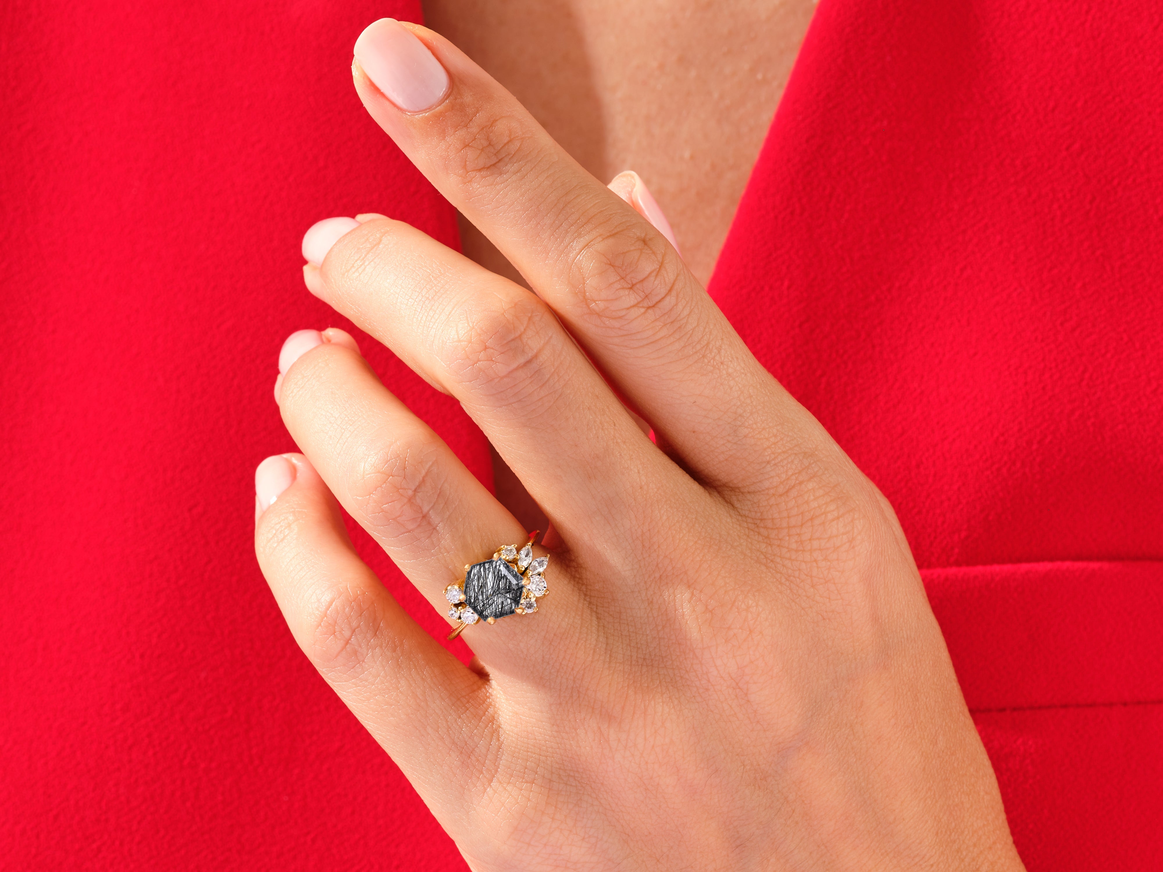 Gold ring with black stone and diamonds on a red background