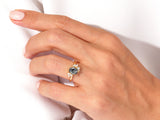 Gold ring with oval grey gemstone and diamonds on hand
