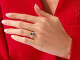 Gold ring with blue sapphire and diamonds on a hand