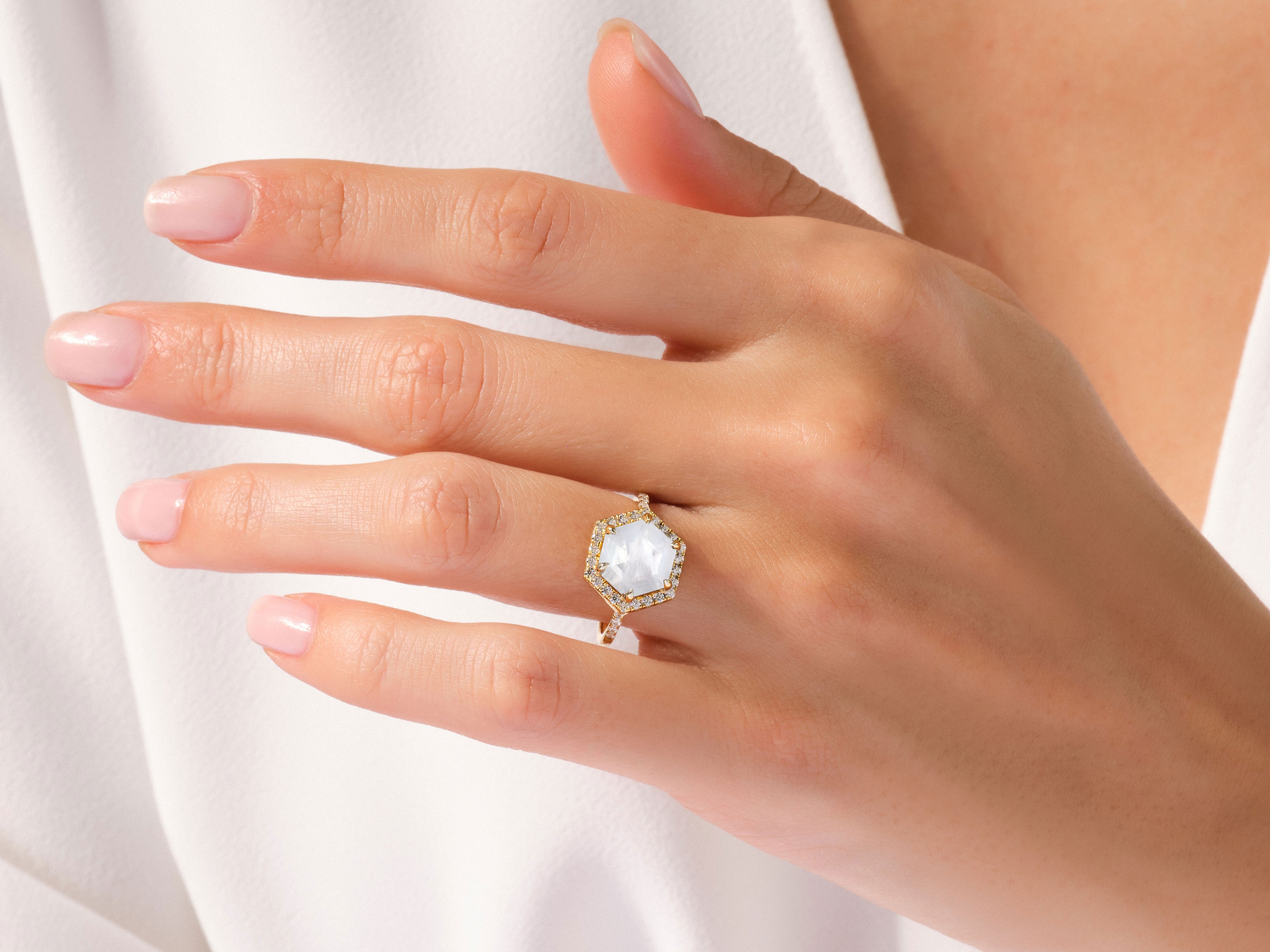 Hexagonal gemstone ring with diamonds on a woman's hand