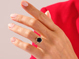 Gold ring with dark blue gemstone and diamonds on a hand