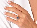 Gold ring with hexagon blue gemstone and diamonds on a hand