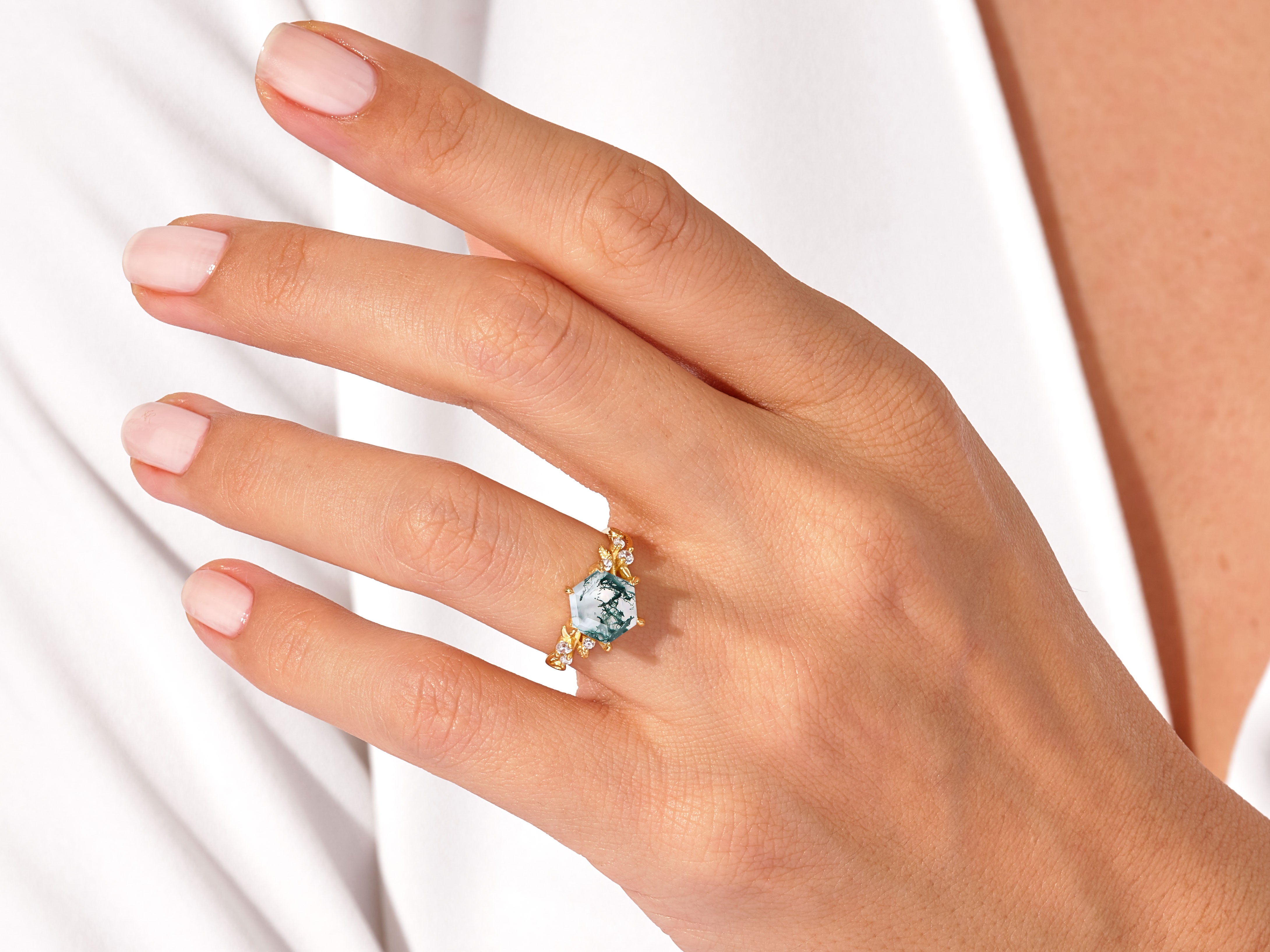 Gold ring with moss agate and diamonds on a woman's hand