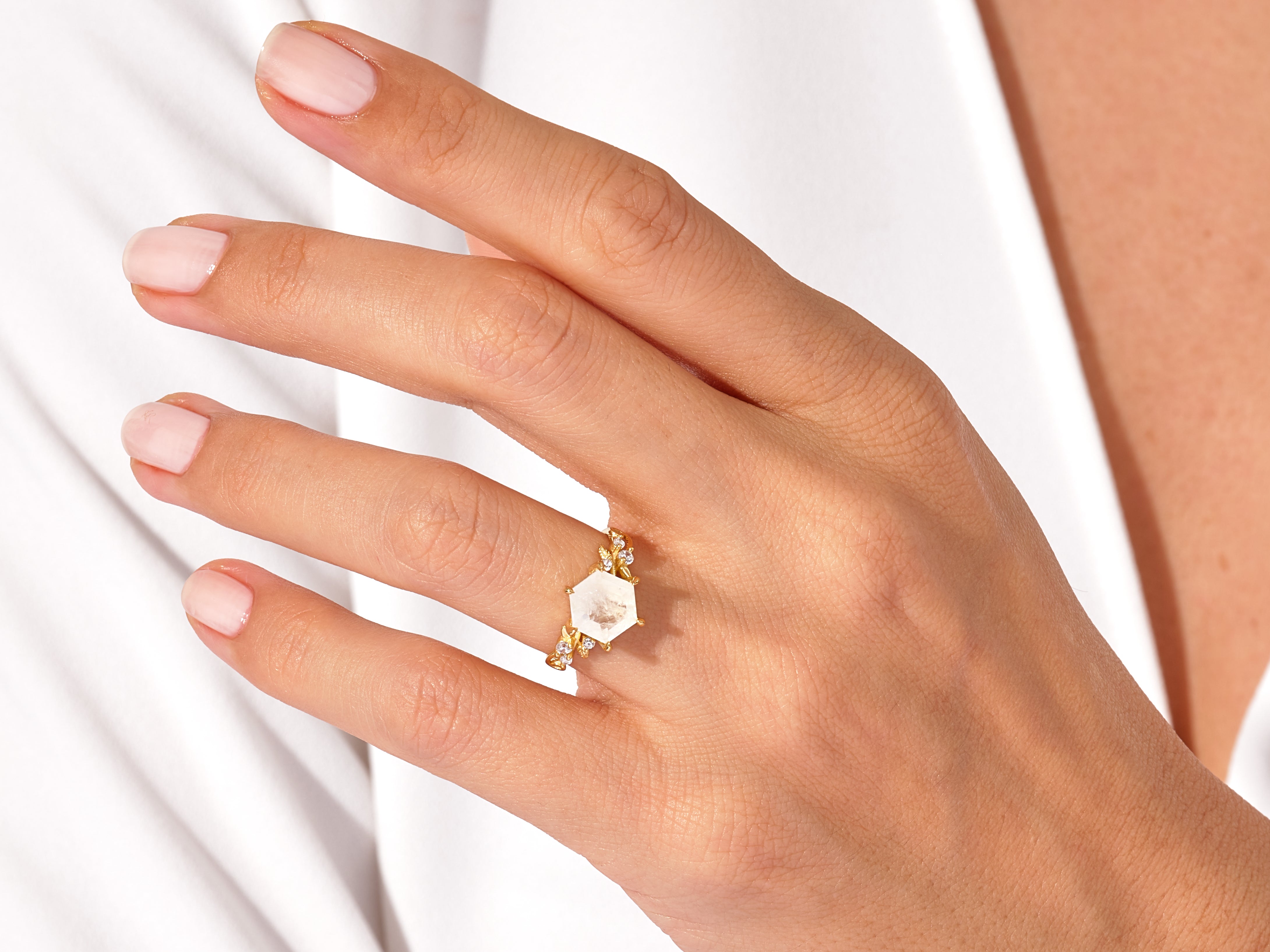 Hexagonal gemstone ring with diamonds on a hand