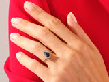 Gold ring with blue gemstone and diamonds on hand