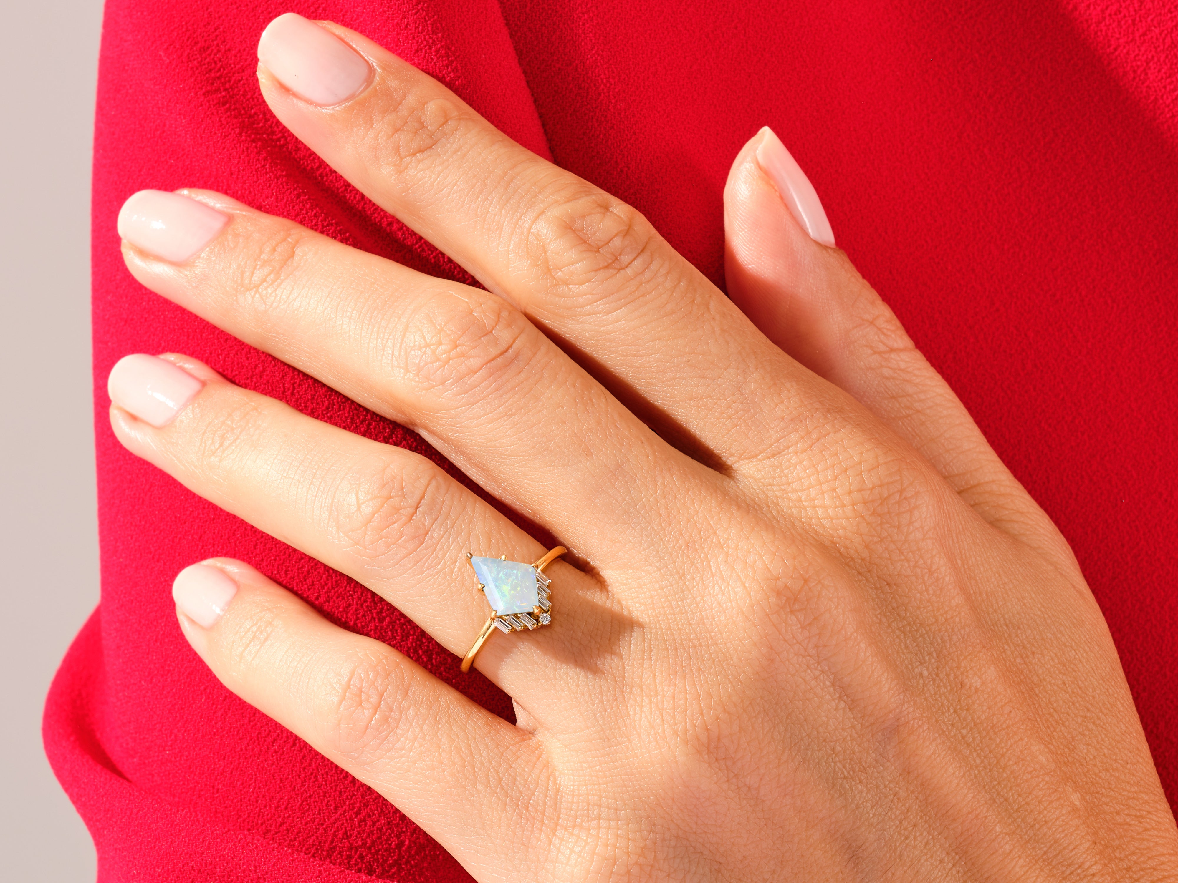 Gold opal ring with diamonds on a hand