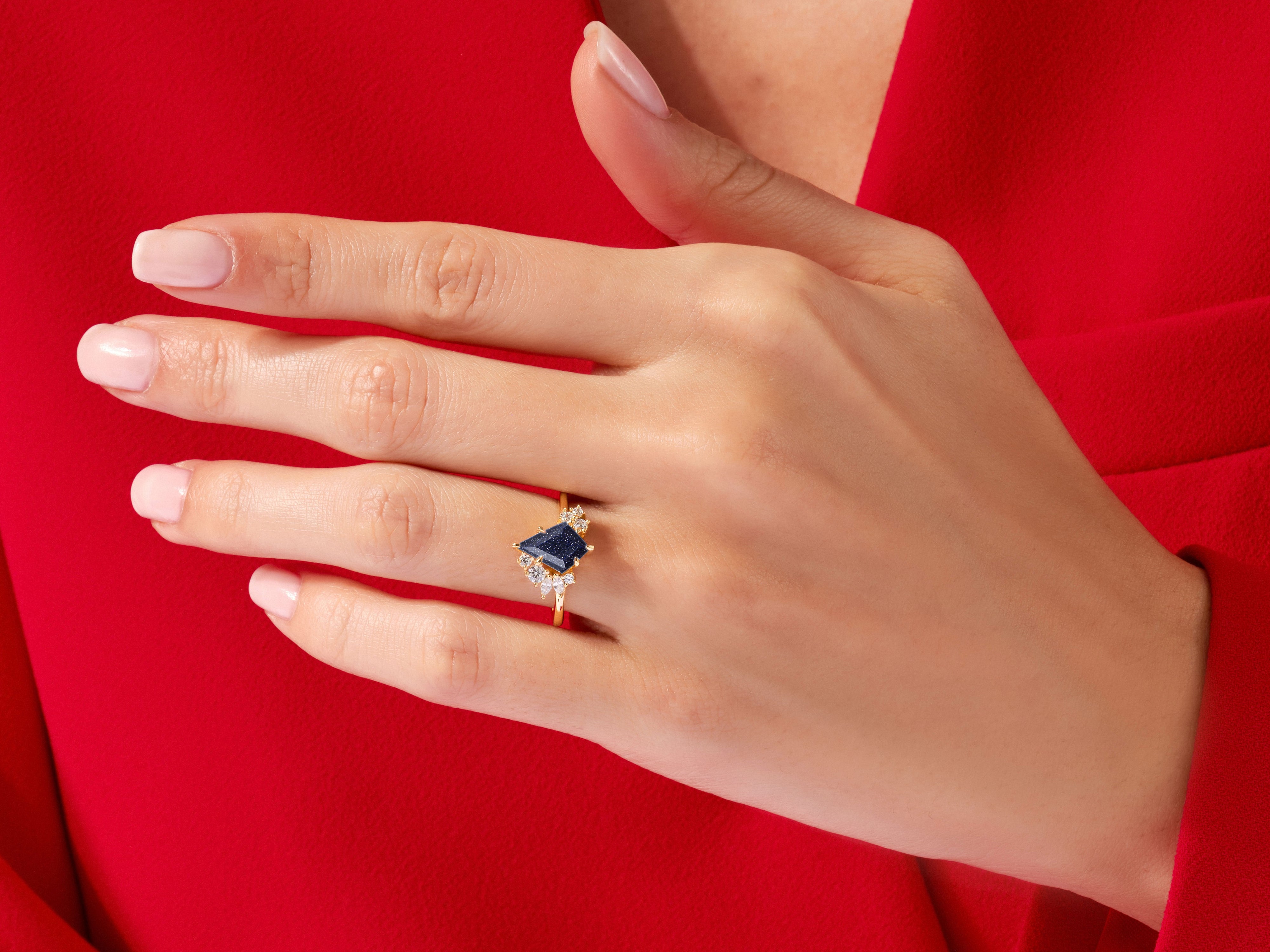 Gold ring with blue gemstone and diamonds on a hand