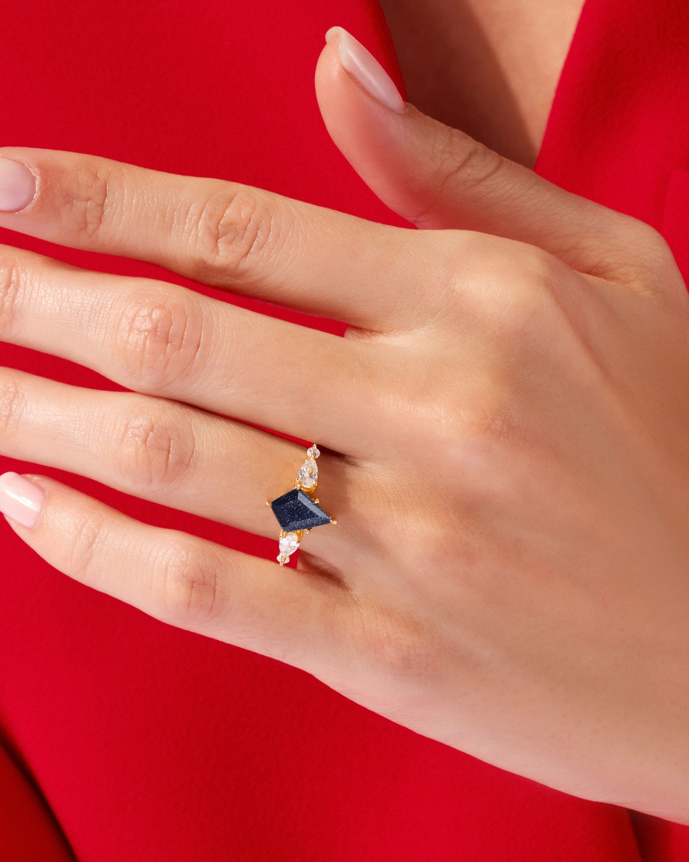Gold ring with dark blue gemstone and diamonds on a hand