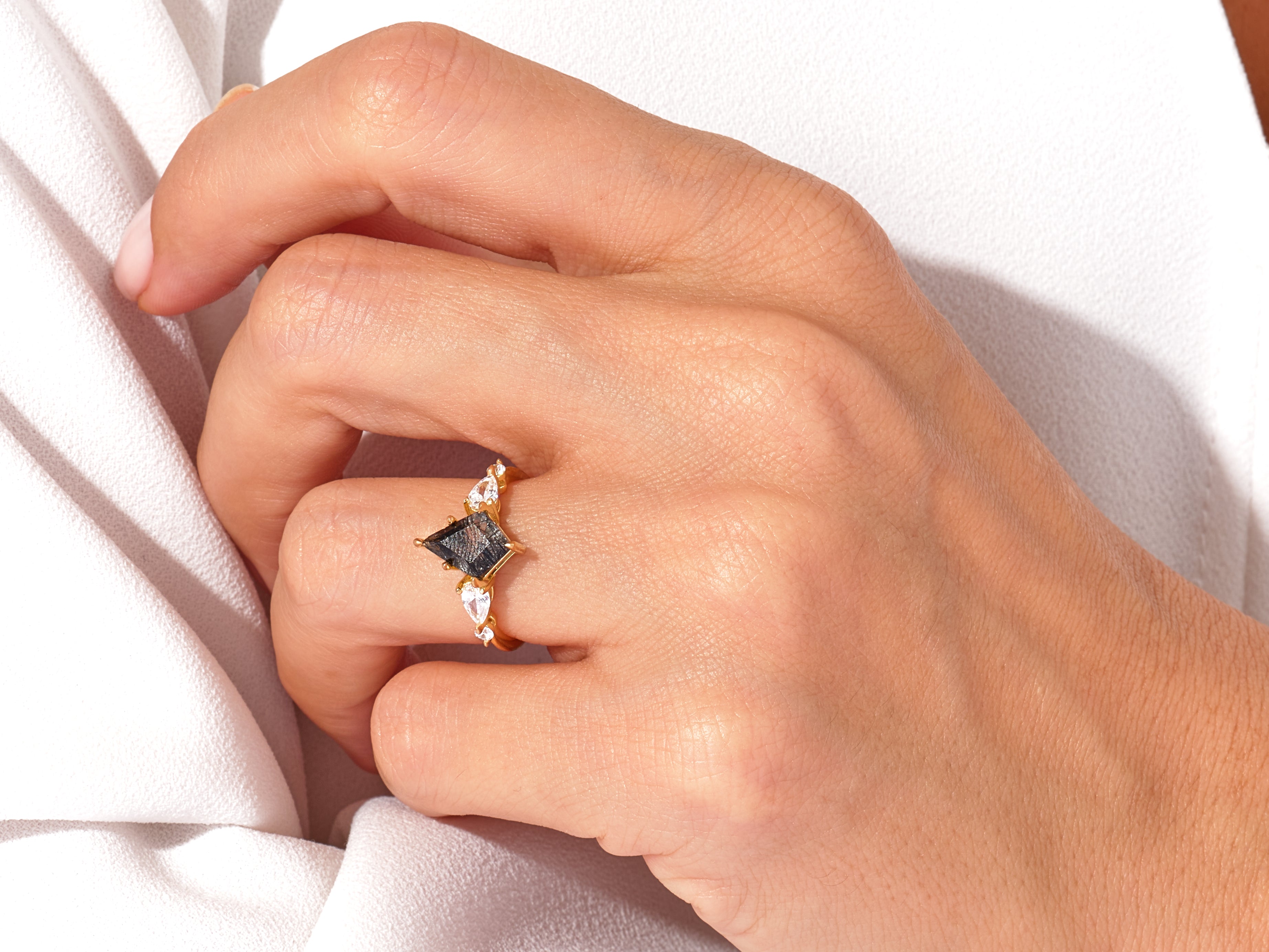 Gold ring with black diamond and white accent stones on hand