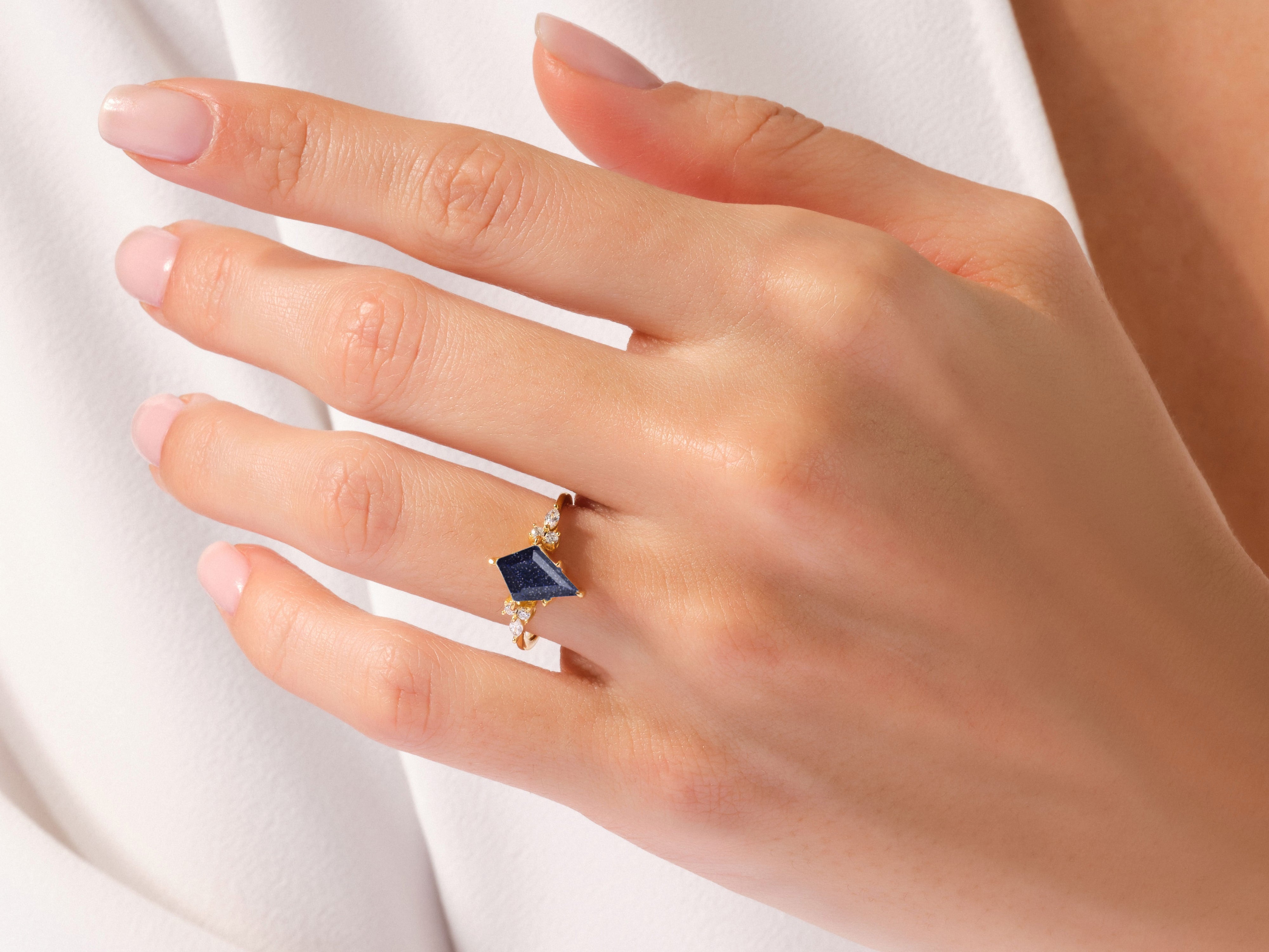 Gold ring with dark blue gemstone and diamonds on a hand