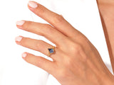 Gold ring with blue gemstone and diamonds on a hand
