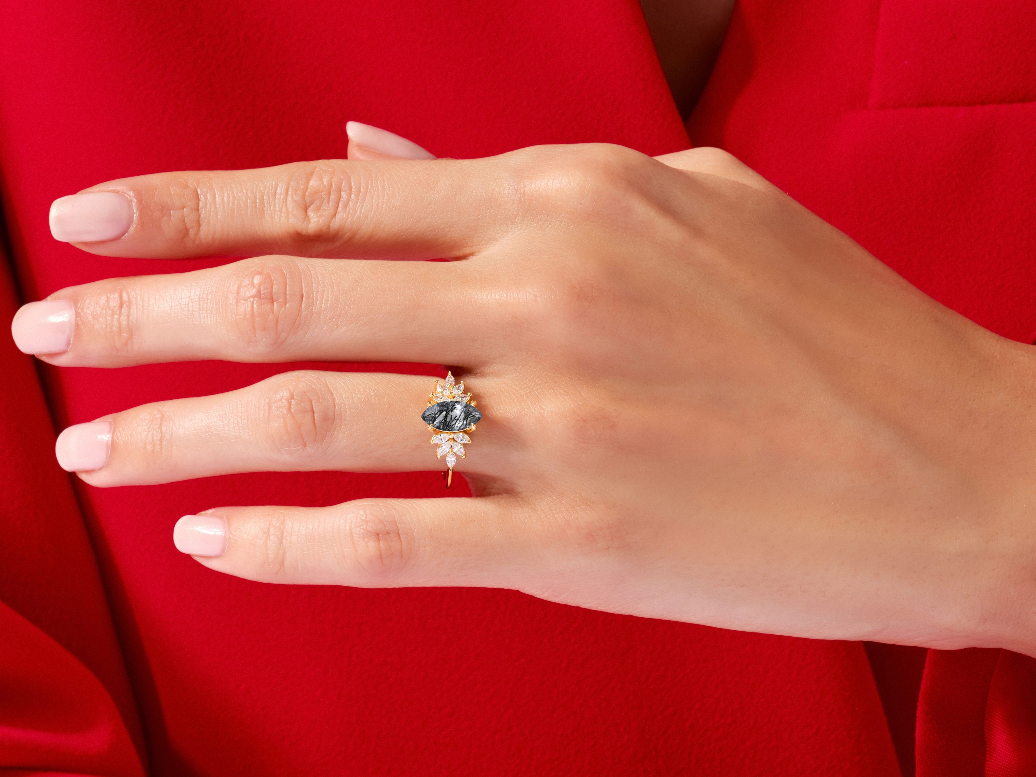 Gold ring with dark gemstone and diamonds on a hand
