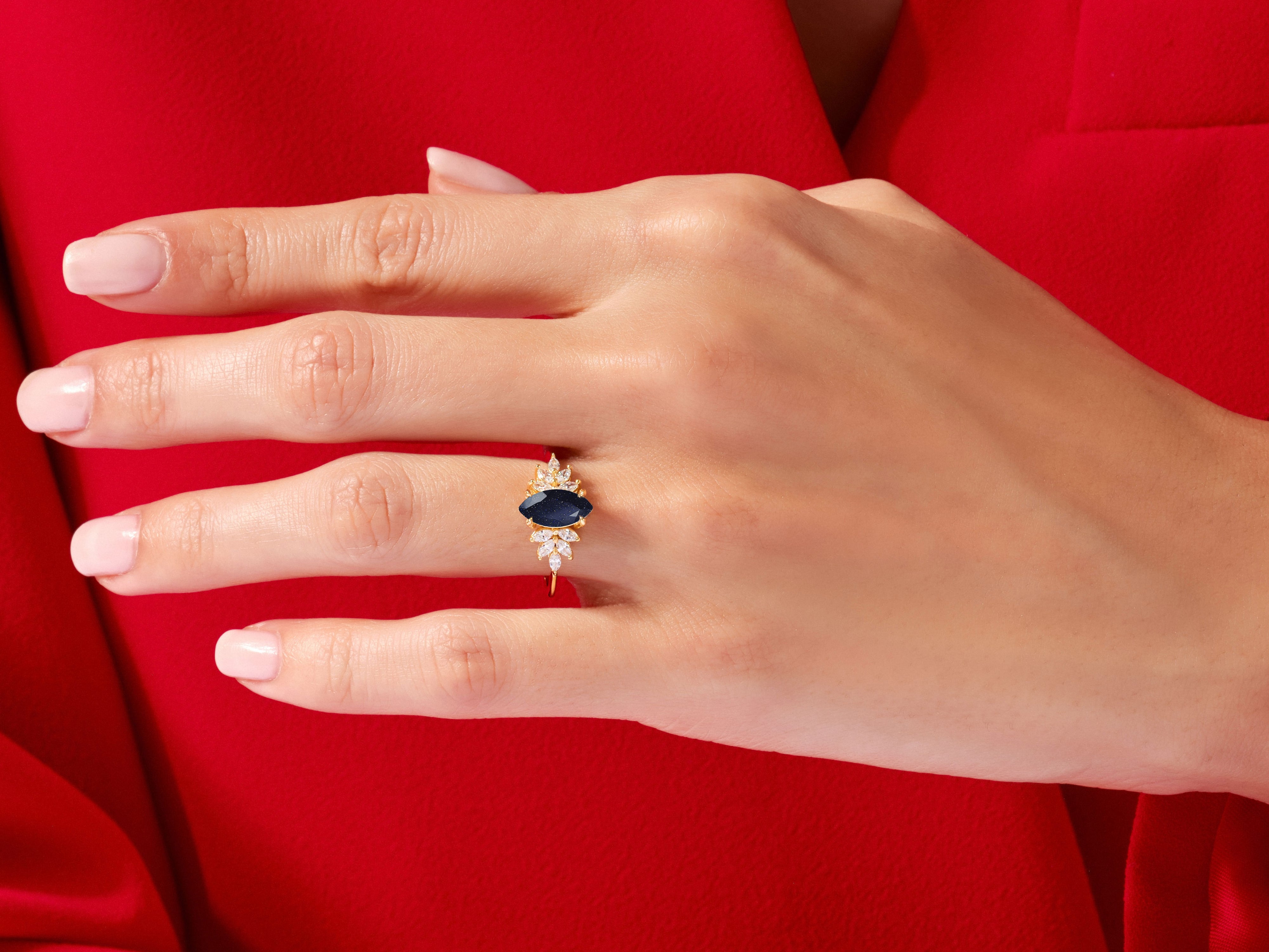 Marquise sapphire ring with diamond accents on a red background