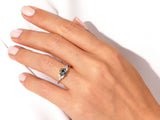 Gold ring with dark center stone and diamonds on a hand