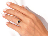 Gold ring with dark blue gemstone and diamonds on hand