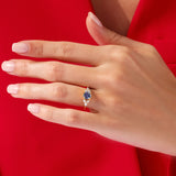 Gold ring with blue sapphire and diamonds on a hand