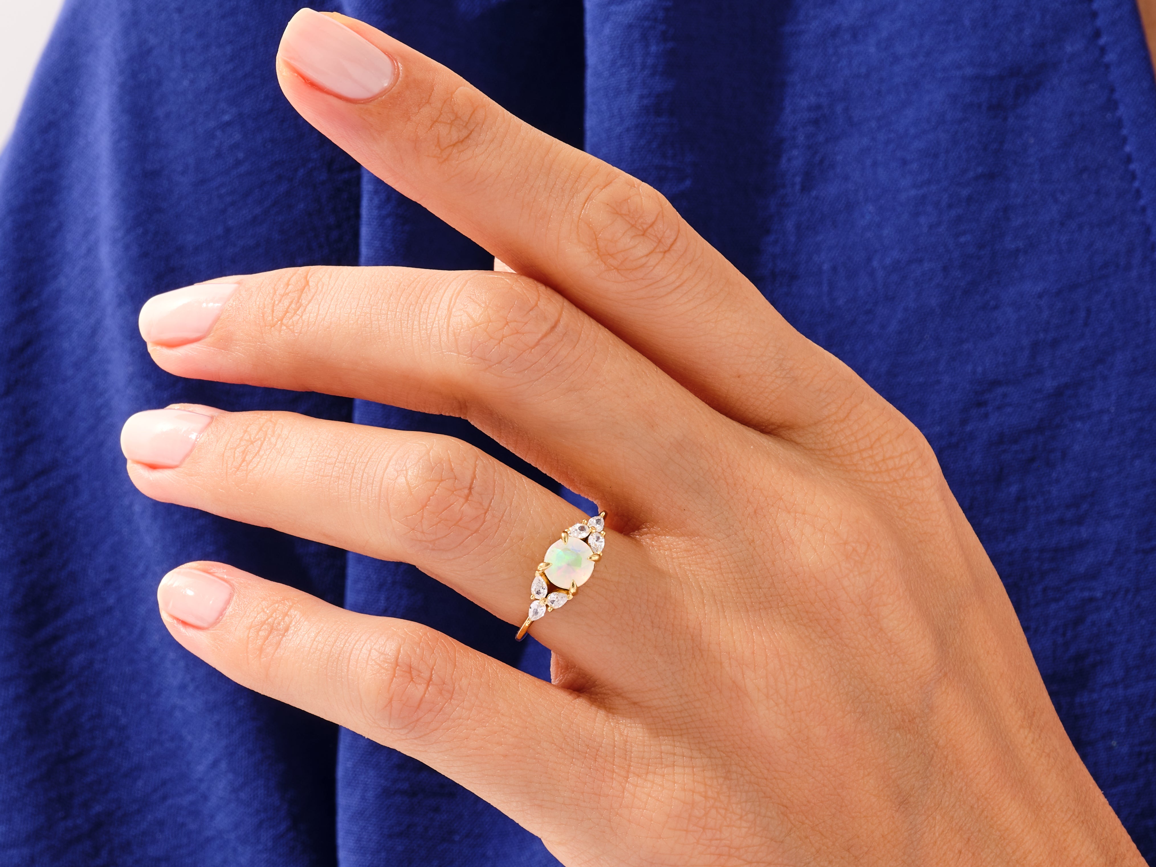 Gold opal ring with diamonds on a hand