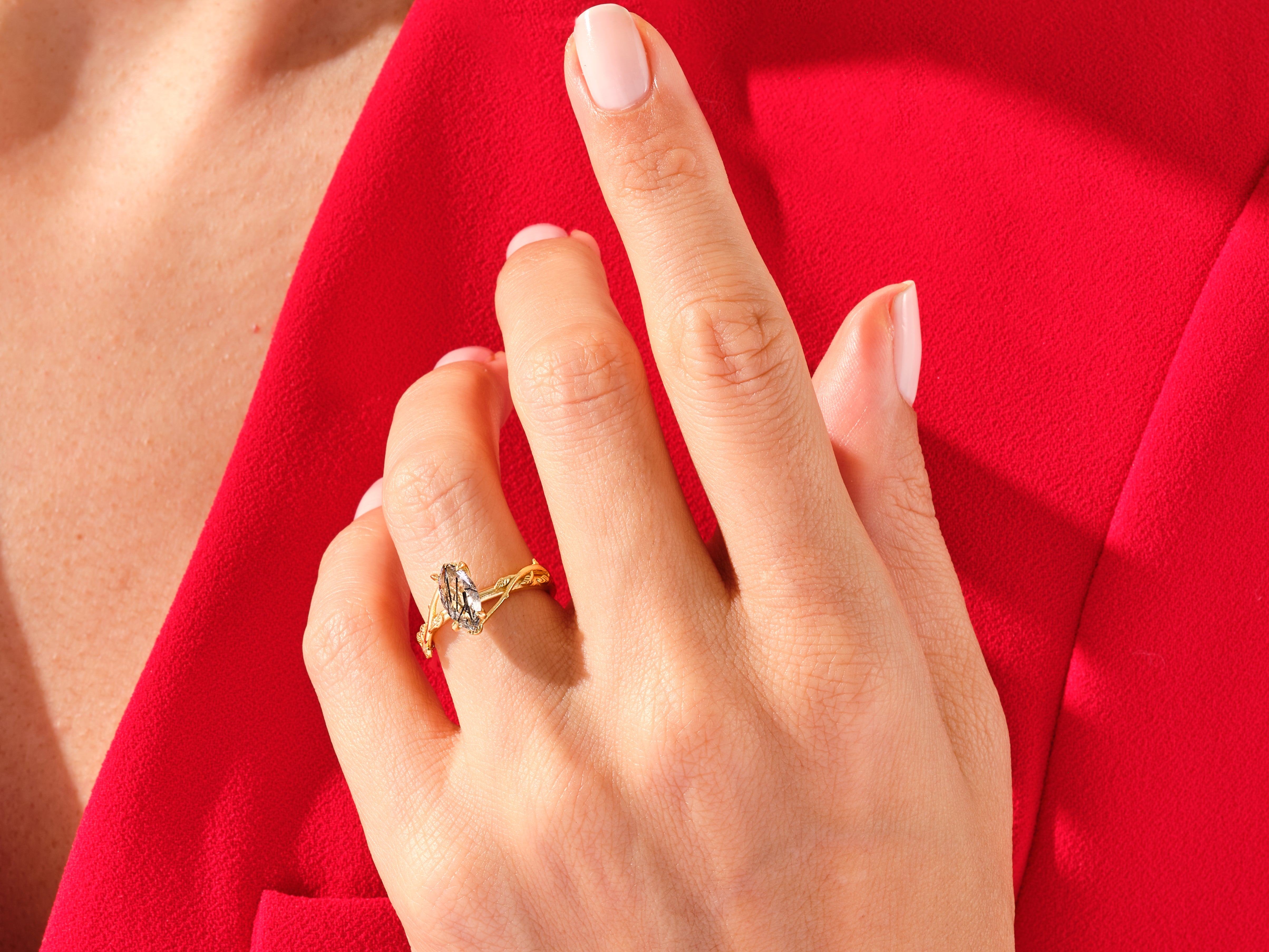Gold ring with unique gemstone on hand against red fabric