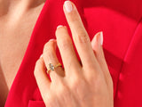 Gold ring with unique gemstone on hand against red fabric