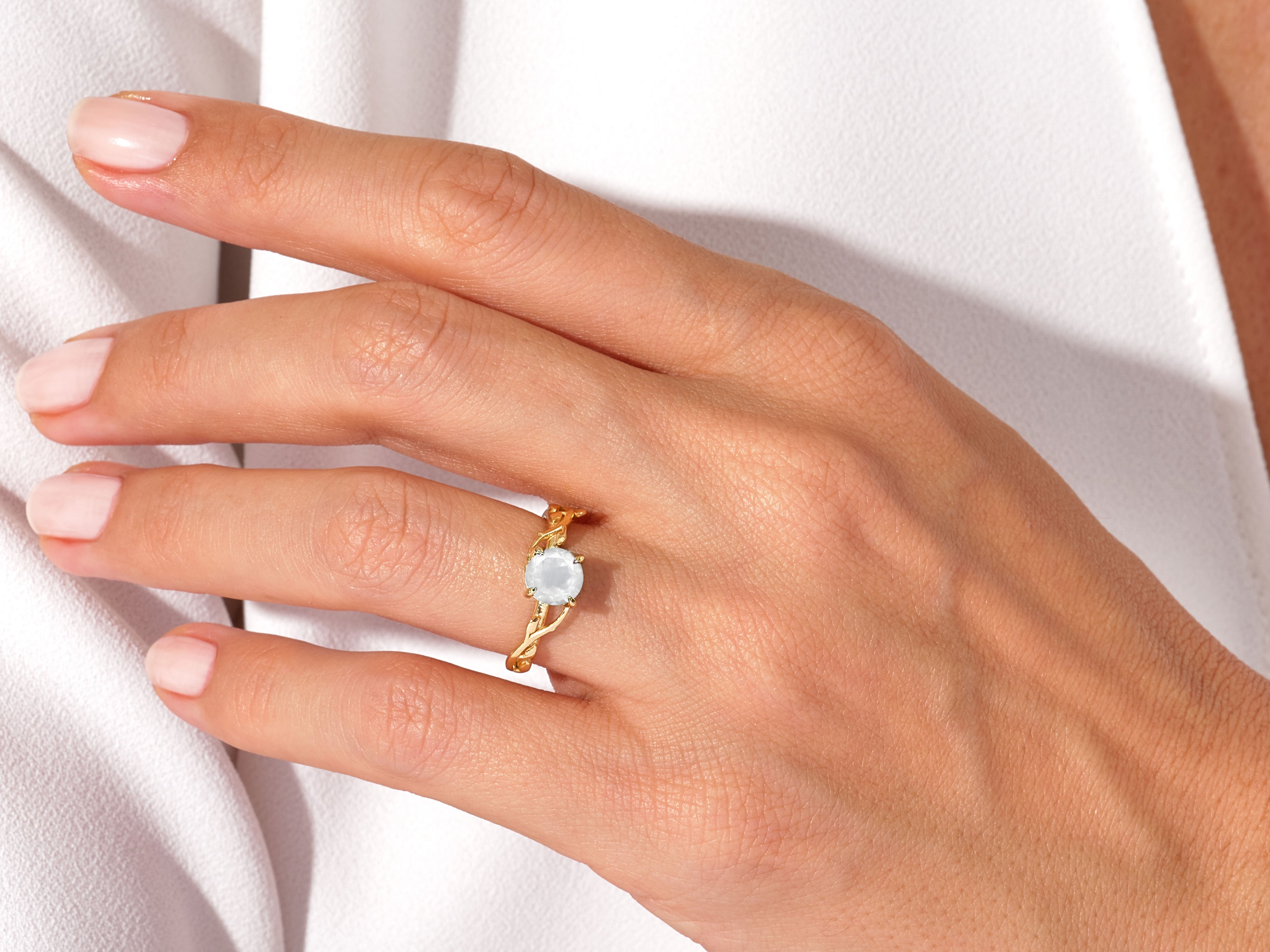 Gold ring with white gemstone on a woman's finger