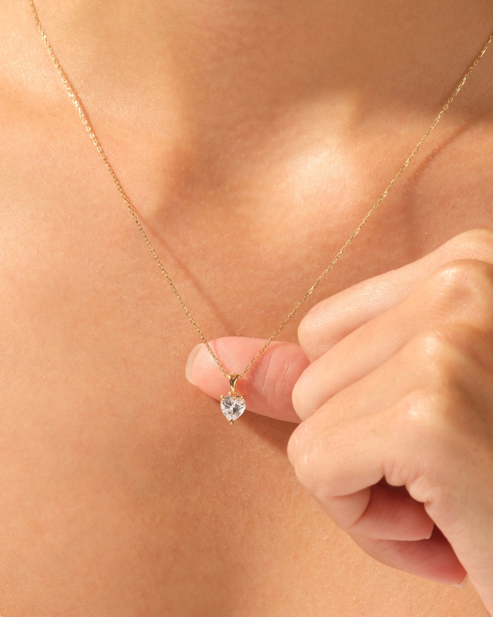 Gold heart necklace with diamond pendant on a woman's neck