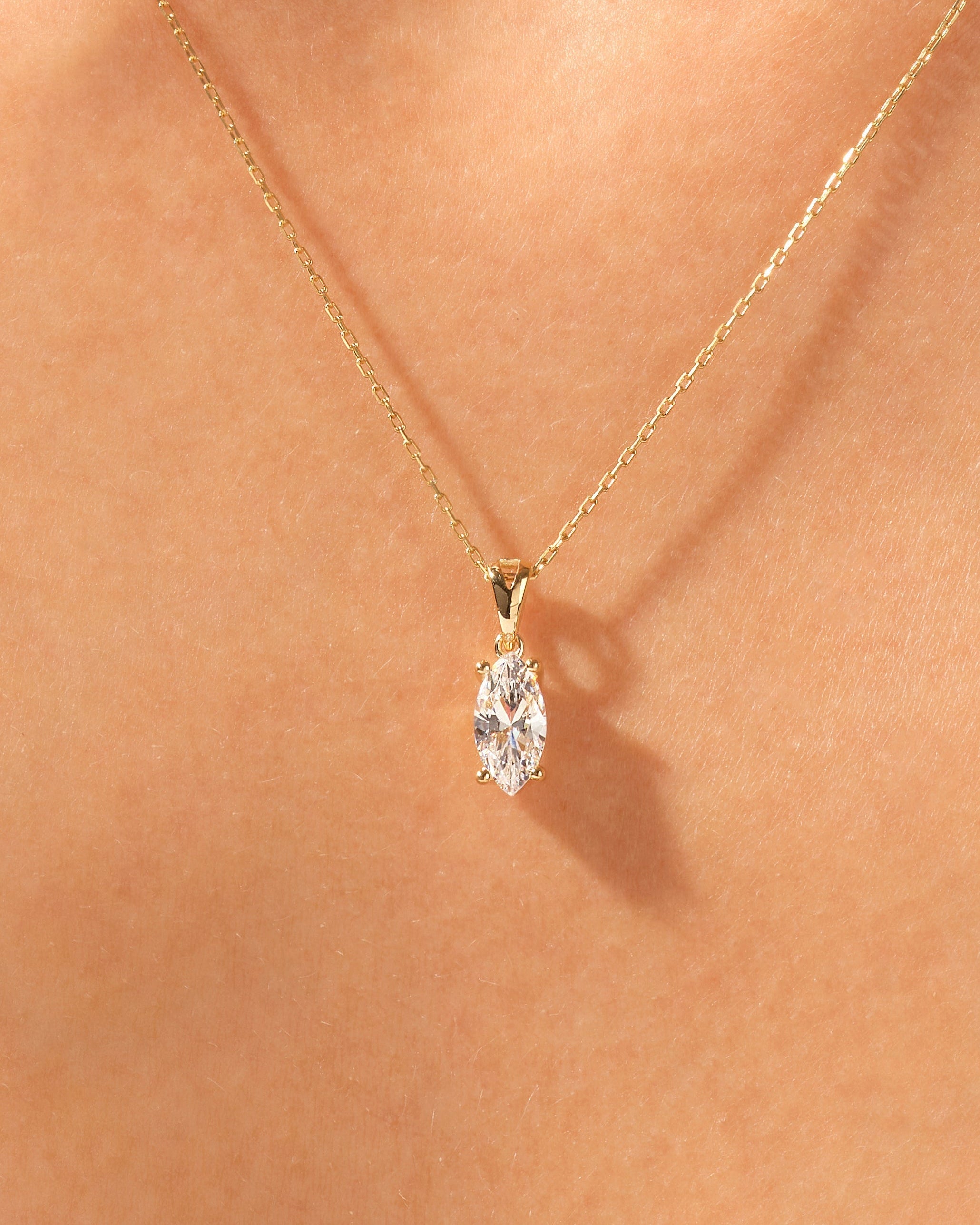 Gold necklace with marquise diamond pendant on skin