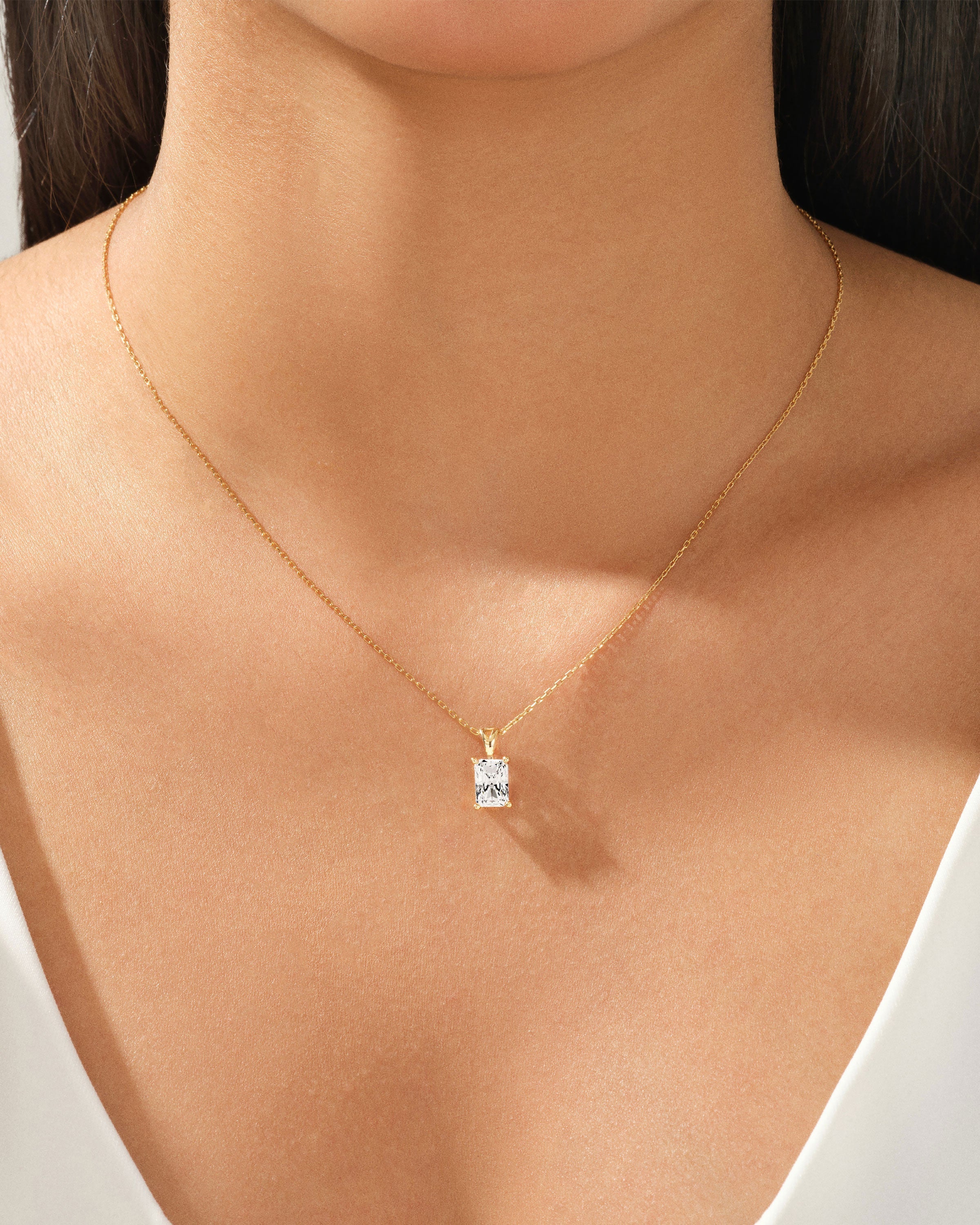 Gold necklace with a square-cut diamond pendant on a woman's neck
