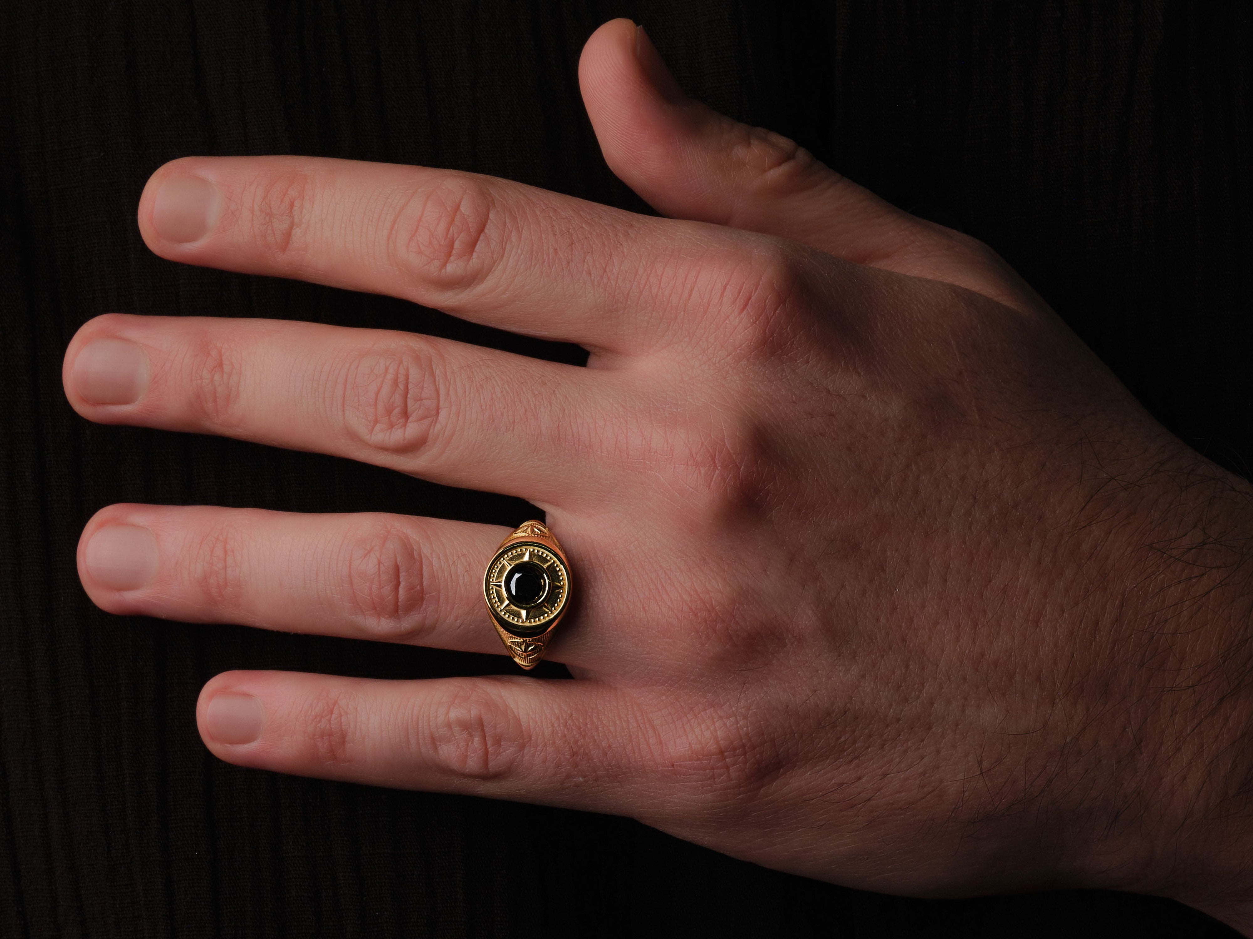 Gold ring with black gemstone on hand